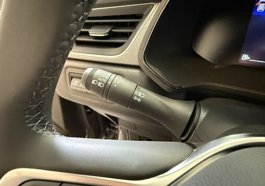 Détail du commodo d’éclairage à gauche du volant dans l’habitacle du Renault Captur gris Cassiopée 2025.