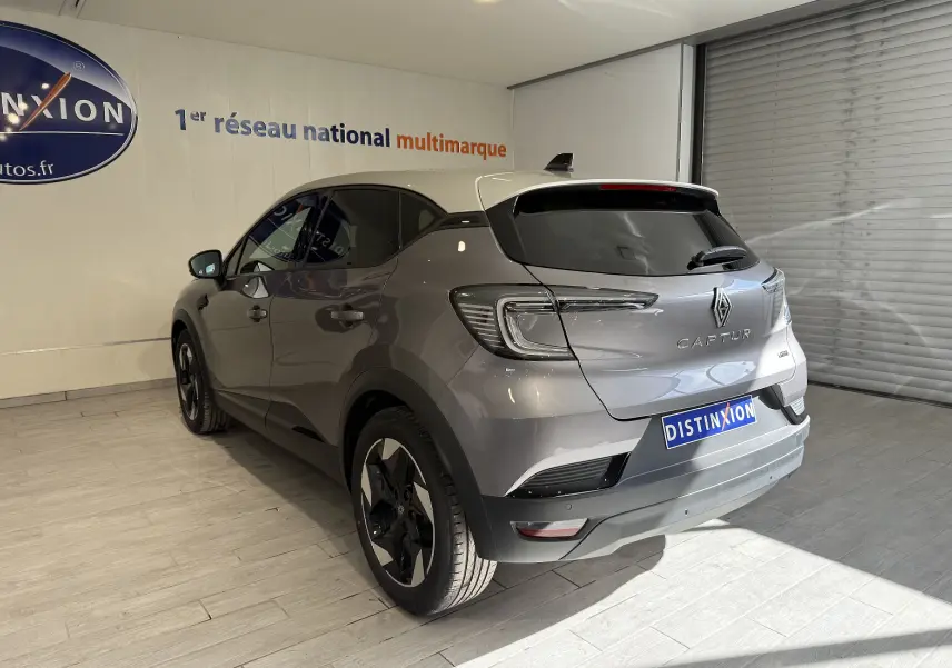 Vue 3/4 arrière droite du Renault Captur 2025 gris Cassiopée métal avec toit gris et jantes noires en showroom.