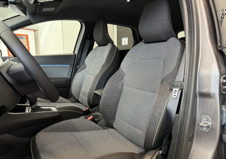 Vue intérieure côté gauche du Renault Captur 2025 gris Cassiopée, montrant les sièges avant en tissu gris et noir.