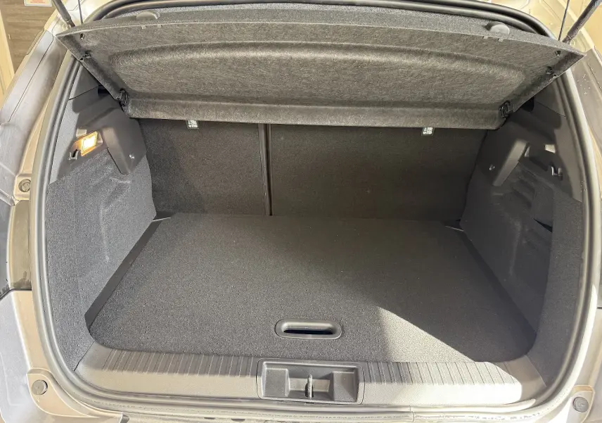 Coffre ouvert vu de l'arrière du Renault Captur gris Cassiopée Métal avec intérieur noir et cache-bagages relevé.
