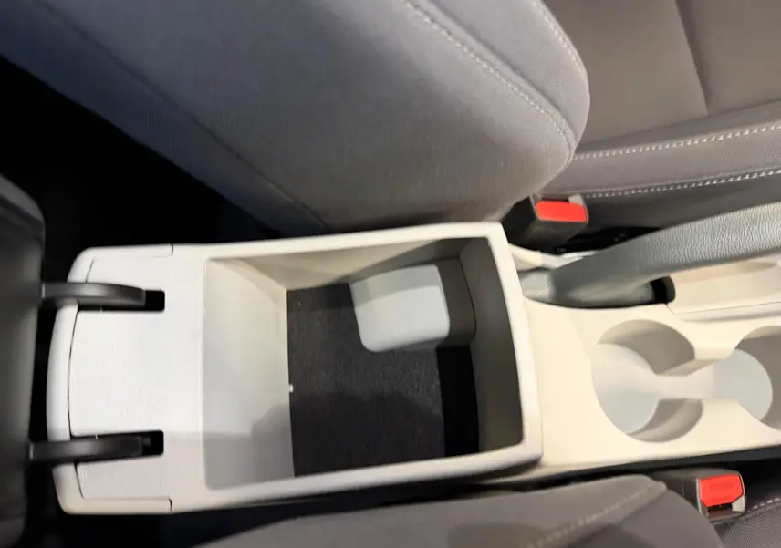 Vue plongeante sur la console centrale beige ouverte du Hyundai Bayon 2025 avec porte-gobelets et sièges gris.