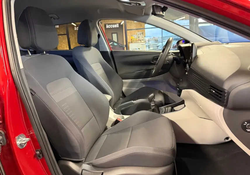 Intérieur avant du Hyundai Bayon rouge 2025, sièges tissu noir, tableau de bord bicolore noir et gris clair.