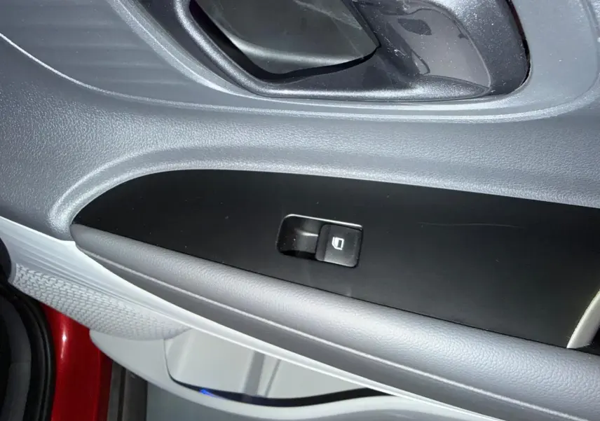 Détail de la commande de vitre côté gauche sur la porte intérieure d'une Hyundai Bayon rouge 2025.