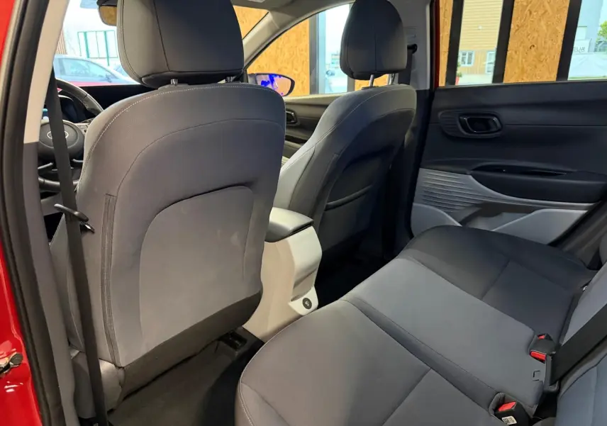 Vue intérieure arrière du Hyundai Bayon rouge 2025, sièges tissu bi-ton noir et gris clair avec accoudoir central.