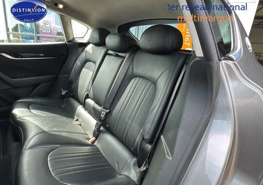 Vue intérieure côté droit montrant la banquette arrière en cuir noir du Maserati Levante gris 2017 avec appuis-tête trident brodés.