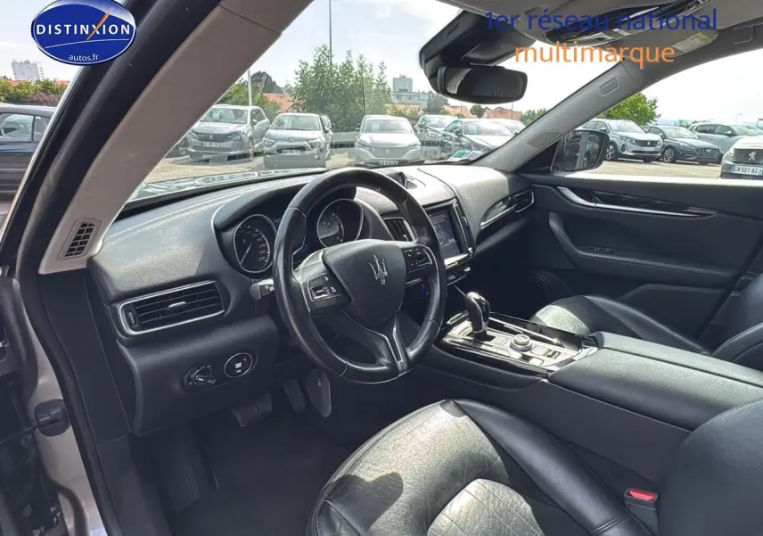 Intérieur côté conducteur du Maserati Levante gris 2017, avec volant cuir et console centrale moderne.