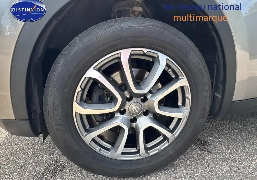 Gros plan sur la roue avant droite avec jante alu grise du Maserati Levante gris 2017.