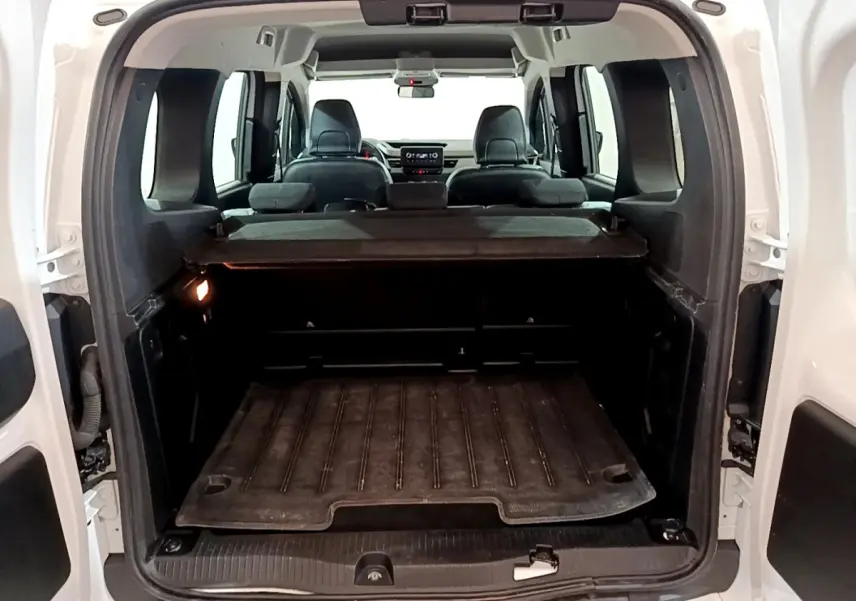 Vue arrière du coffre ouvert du Renault Kangoo blanc 2022, montrant l’espace de chargement et les sièges arrière rabattus.