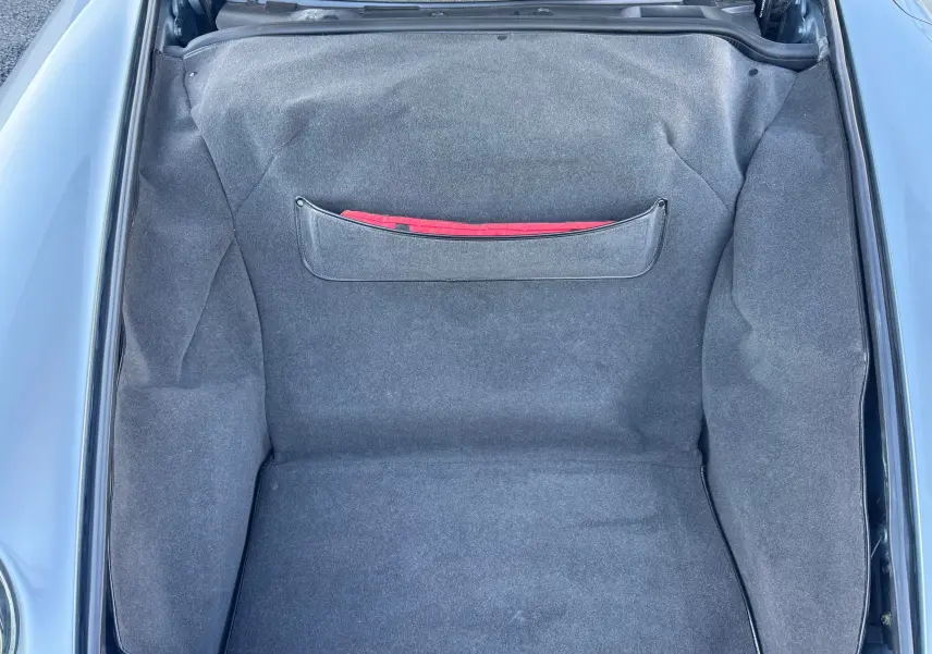 Vue plongeante sur le coffre avant gris polaire d'une Porsche 911 Carrera 993 de 1996, intérieur tissu gris avec pochette rouge.