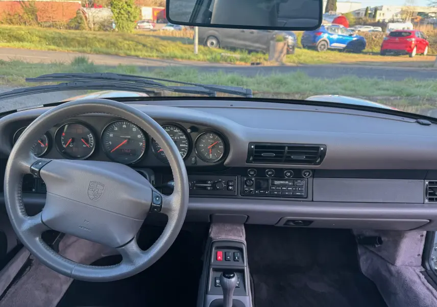 Vue intérieure du tableau de bord et volant gris d'une Porsche 911 Carrera 2 Type 993 de 1996 avec boîte automatique.