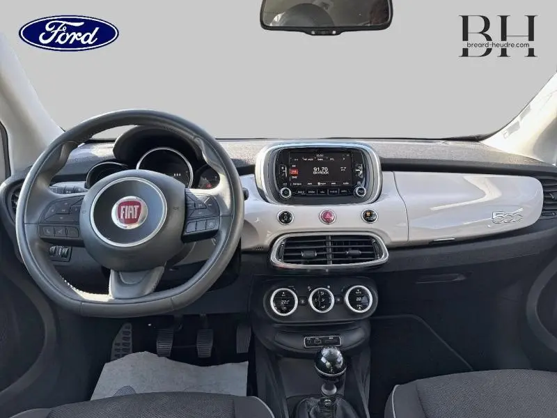 Vue intérieure avant du tableau de bord argenté et volant cuir multifonction d'une Fiat 500X 2015 avec boîte manuelle.