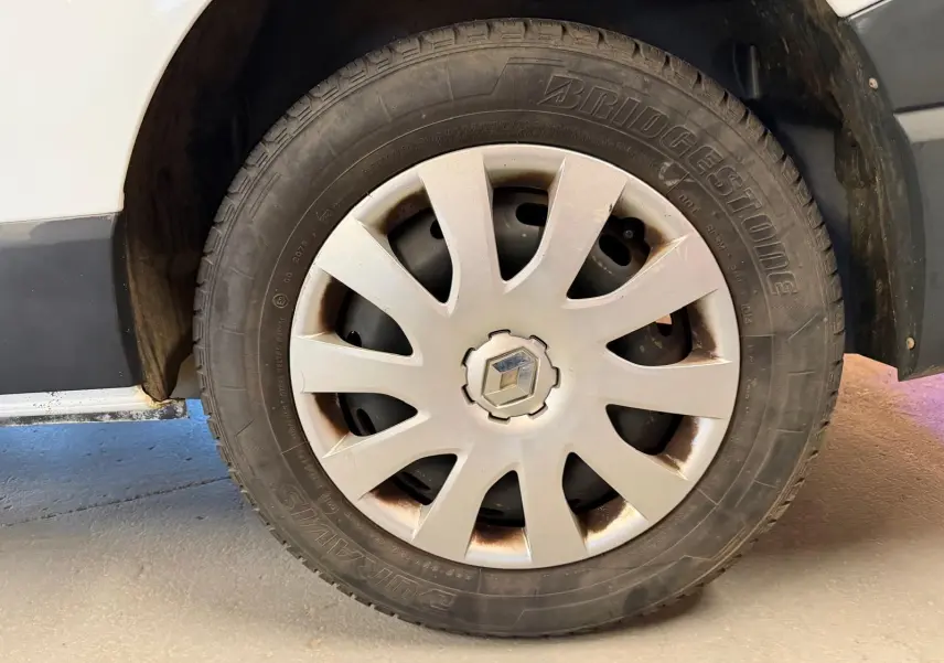 Gros plan sur la roue avant gauche blanche d’un Renault Trafic Fourgon 2017 avec jante en plastique gris clair.