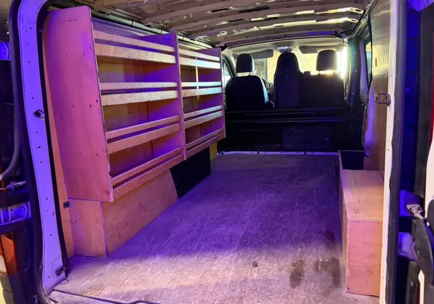 Vue intérieure arrière du Renault Trafic blanc 2017 avec aménagements en bois sur le côté gauche et droite.