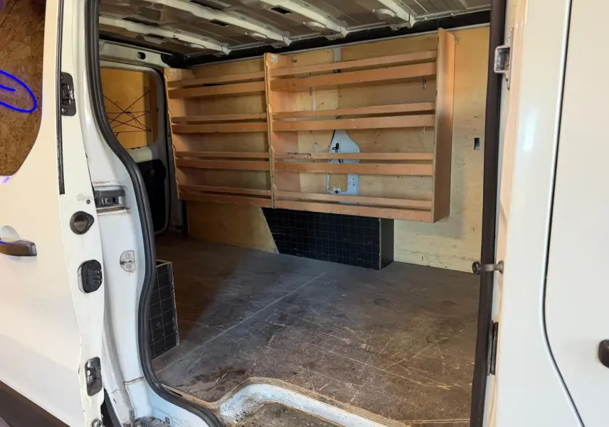 Vue intérieure côté droit du Renault Trafic blanc 2017 avec habillage bois et étagères dans l’espace de chargement.