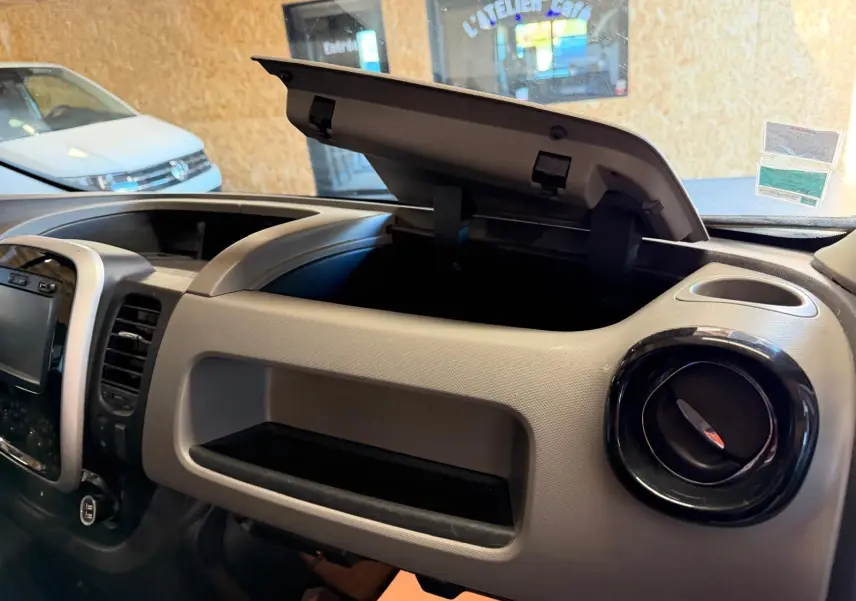 Vue intérieure du tableau de bord du Renault Trafic Fourgon blanc 2017, avec boîte à gants ouverte et habillage bois visible.