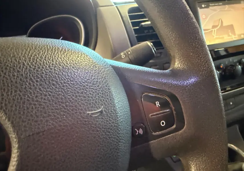 Gros plan sur le volant noir du Renault Trafic Fourgon 2017 avec commandes intégrées et écran GPS en arrière-plan.