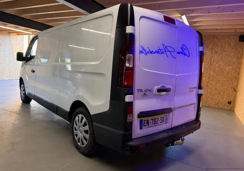 Vue 3/4 arrière droite du Renault Trafic Fourgon blanc de 2017 avec attelage et habillage bois visible en intérieur.