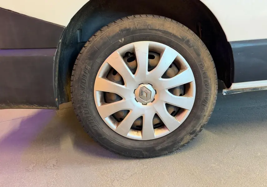 Gros plan sur la roue avant gauche d’un Renault Trafic blanc, avec jante en alliage et logo Renault visible.