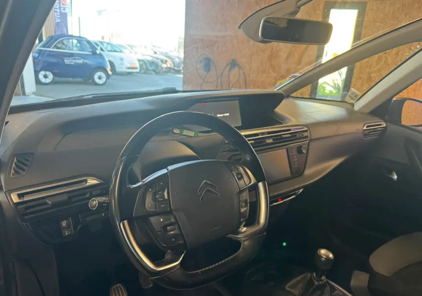 Intérieur de Citroën C4 Picasso gris, vue côté conducteur, volant cuir multifonctions et tableau de bord moderne.