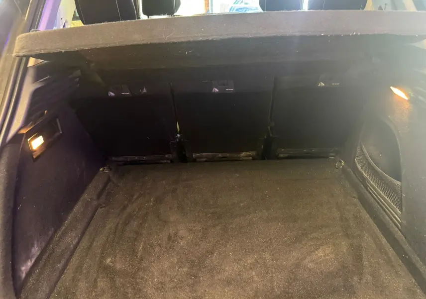 Coffre ouvert vu de l'arrière d'une Citroën C4 Picasso 2016, intérieur noir avec éclairage latéral.