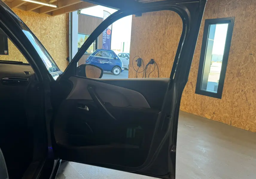 Vue intérieure côté gauche de la porte avant ouverte d'une Citroën C4 Picasso gris 2016 dans un garage.
