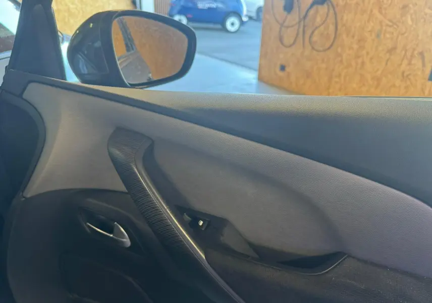 Vue intérieure de la porte côté conducteur de la Citroën C4 Picasso gris, avec poignée noire et bouton de commande vitre.
