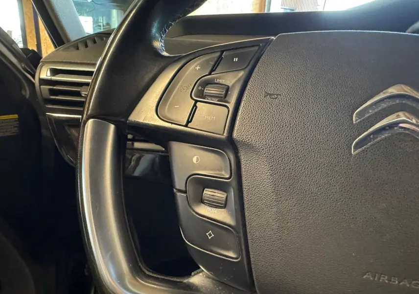 Gros plan sur le volant cuir noir multifonctions de la Citroën C4 Picasso 2016, avec commandes intégrées.