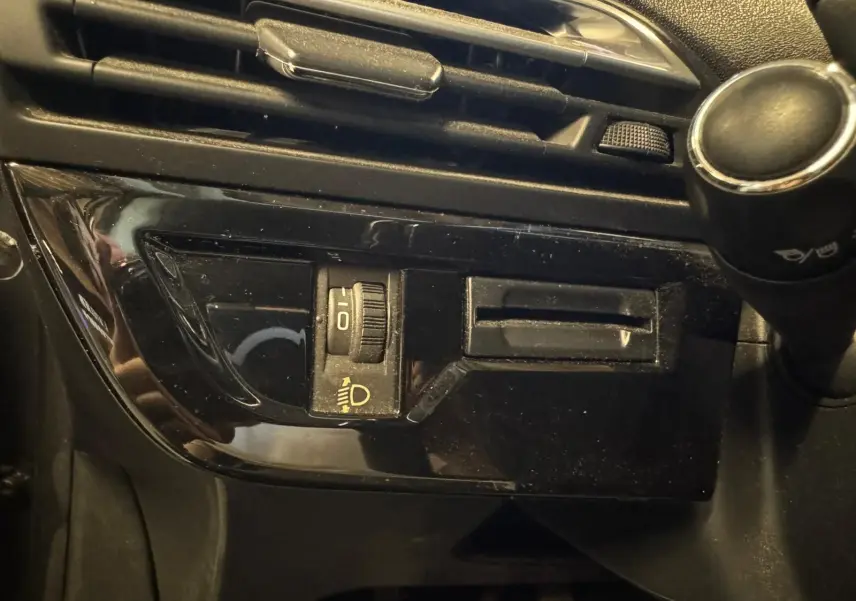 Gros plan sur le tableau de bord noir du Citroën C4 Picasso 2016, montrant la molette de réglage des phares.