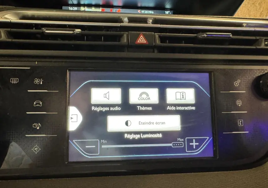 Vue rapprochée de l'écran tactile central du tableau de bord de la Citroën C4 Picasso gris, affichant les réglages audio et luminosité.
