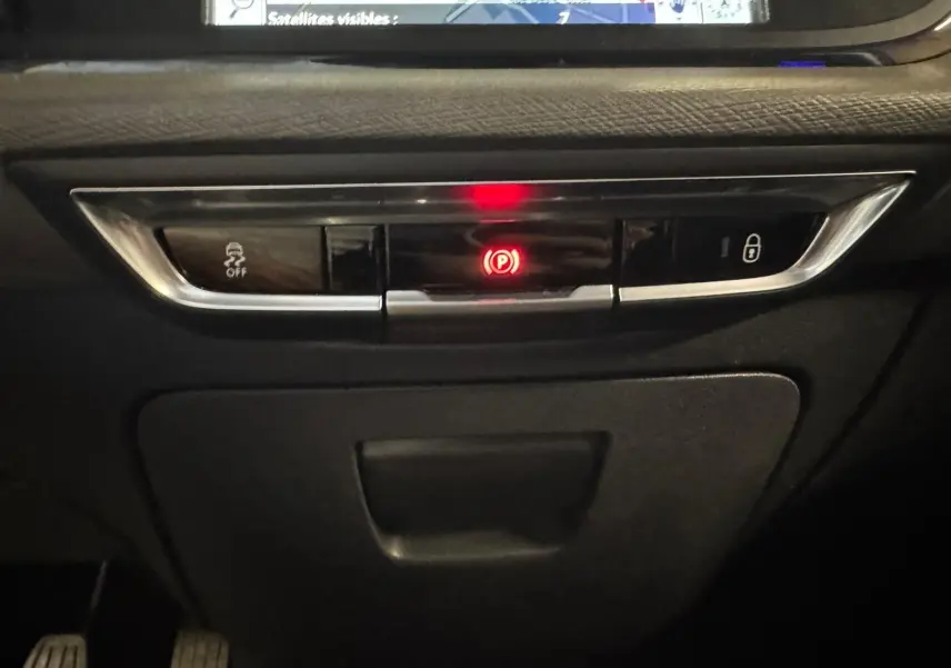 Gros plan sur la console centrale noire du Citroën C4 Picasso 2016 avec bouton de frein à main électronique allumé en rouge.