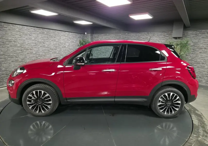 Vue latérale droite d'un Fiat 500X rouge Passione avec jantes alliage 17 pouces et vitres surteintées.