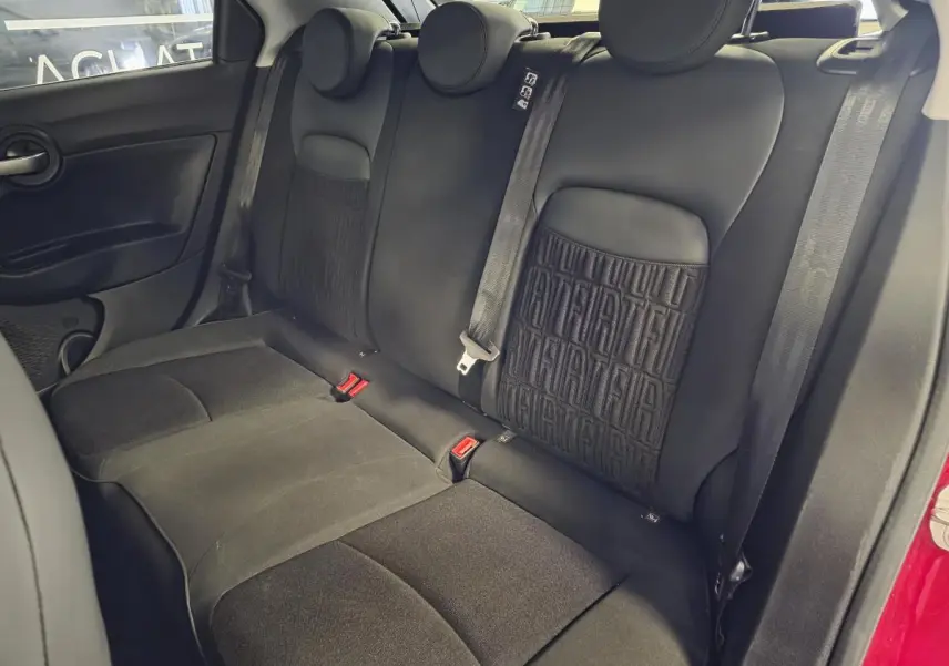 Vue intérieure de la banquette arrière noire avec monogramme FIAT, côté droit du Fiat 500X rouge 2024.