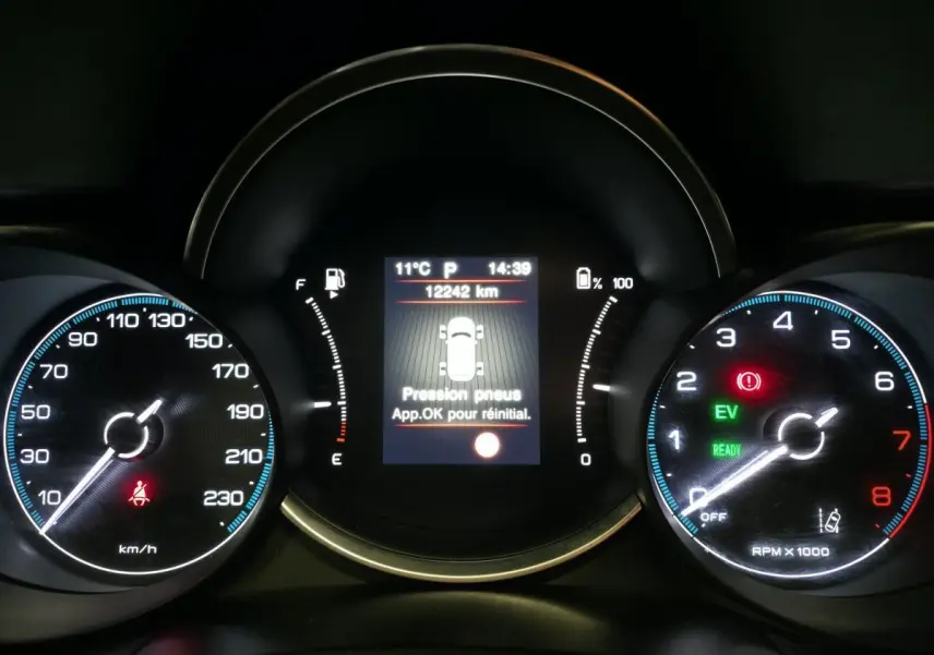 Tableau de bord de Fiat 500X 2024 avec affichage numérique central et compteurs analogiques éclairés en bleu et rouge.