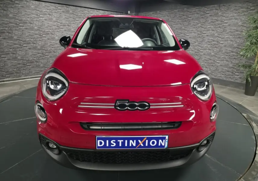 Vue avant d'une Fiat 500X rouge vif avec phares LED ronds et calandre noire dans un showroom.