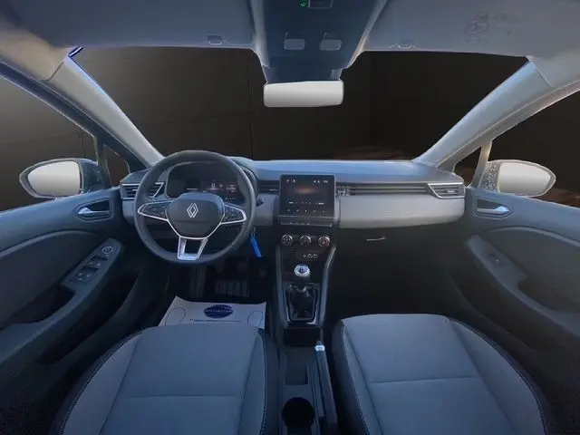 Vue intérieure avant de la Renault Clio gris foncé 2025, tableau de bord avec écran tactile central et volant multifonctions.