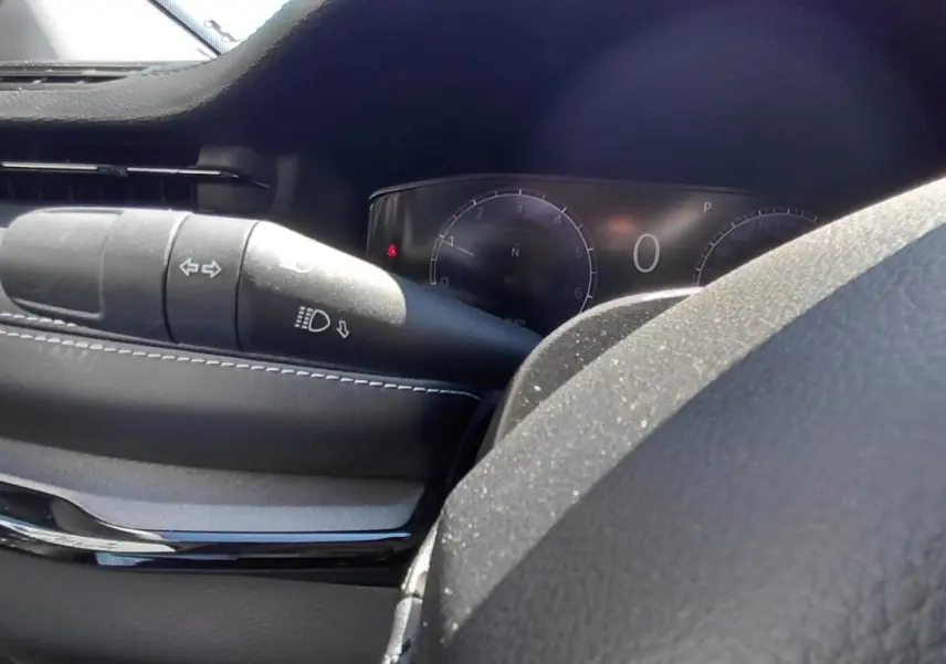 Gros plan sur le commodo de clignotants et phares du tableau de bord noir du Jeep Compass 2025.