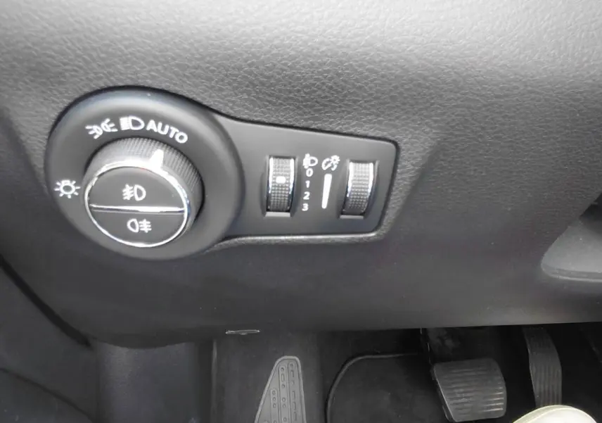Gros plan sur les commandes d’éclairage et réglages du tableau de bord du Jeep Compass noir, côté conducteur.