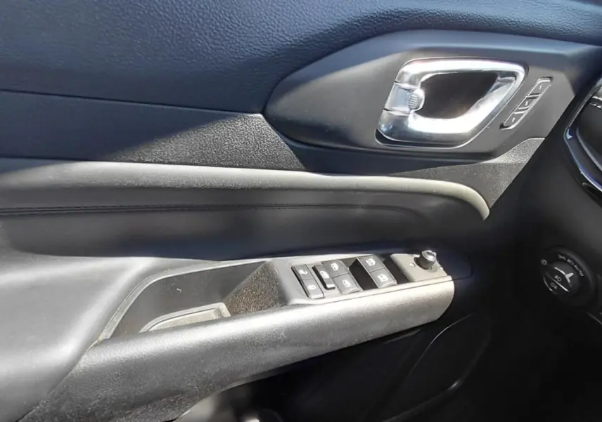 Détail de la porte côté conducteur du Jeep Compass 2025 noir, avec commandes des vitres et poignée chromée.