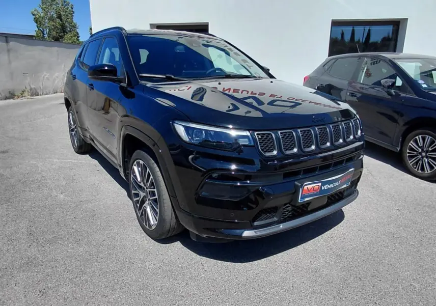 Jeep Compass noir vu en 3/4 avant droit, avec jantes alliage 19 pouces et barres de toit visibles.