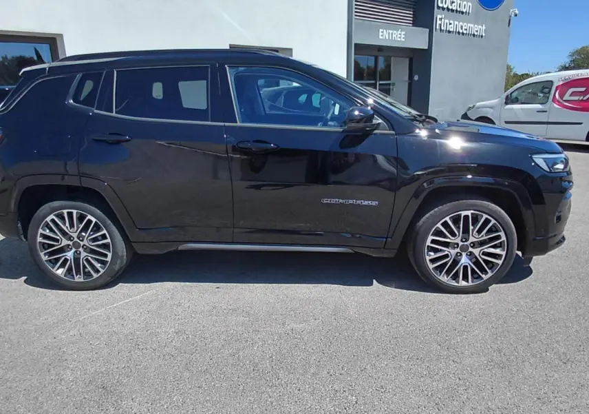 Jeep Compass noir vu de profil côté gauche, avec jantes alliage 19 pouces et barres de toit visibles.
