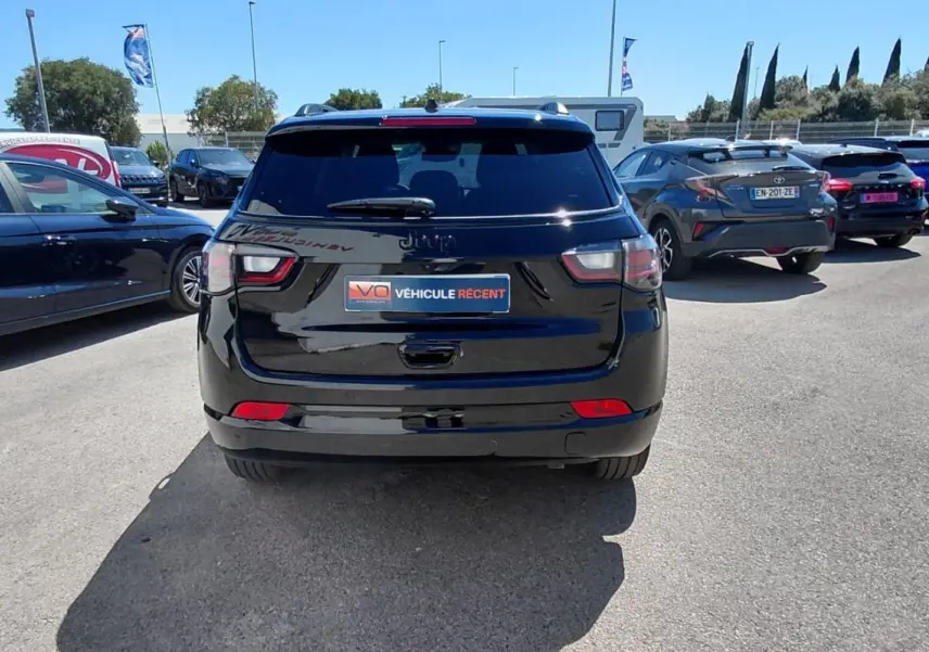 Vue arrière d'un Jeep Compass noir 2025 avec barres de toit et jantes alliage 19 pouces, stationné en extérieur.
