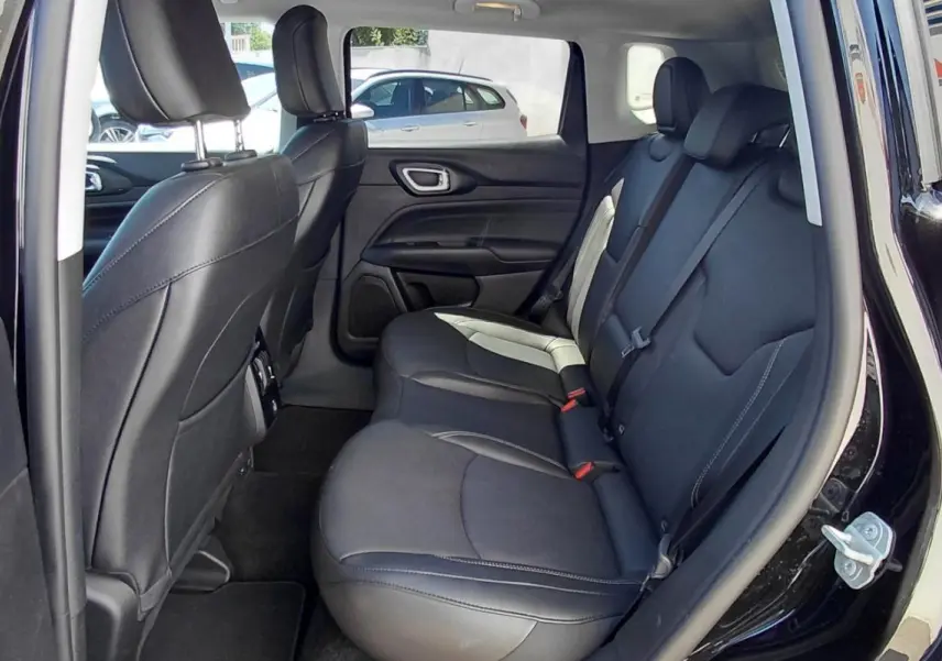 Vue intérieure côté gauche des sièges arrière en cuir noir du Jeep Compass 2025 noir avec accoudoir central et finitions contrastées.