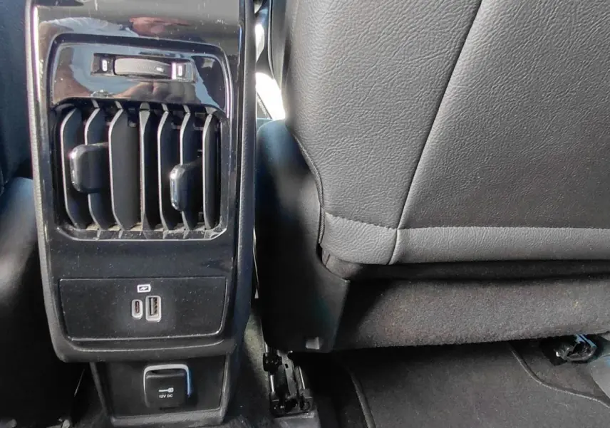 Vue rapprochée de la console arrière noire du Jeep Compass 2025 avec prises USB, prise 12V et aérateurs.