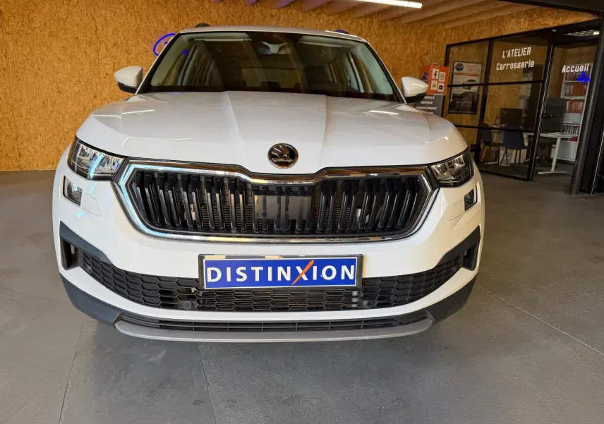 Vue 3/4 avant droite d'un Skoda Kodiaq blanc 2023 avec calandre chromée et phares LED distinctifs.