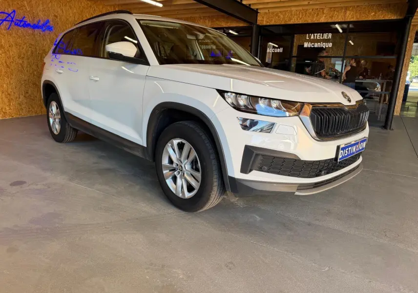 Vue 3/4 arrière droite d'un Skoda Kodiaq blanc 2023, SUV 7 places avec feux arrière LED et toit noir.