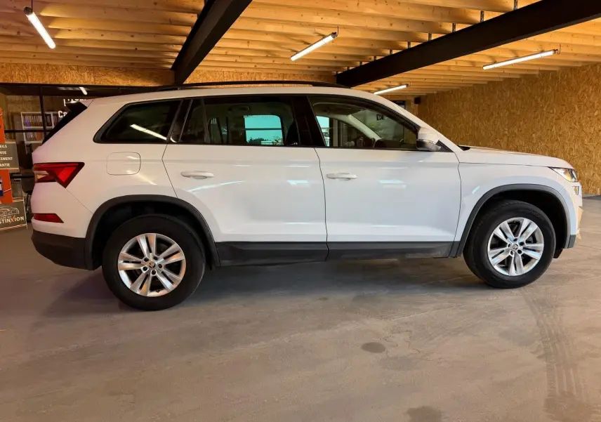Vue 3/4 arrière droite d'un Skoda Kodiaq blanc 2023 avec toit noir et jantes en alliage, sur fond neutre.