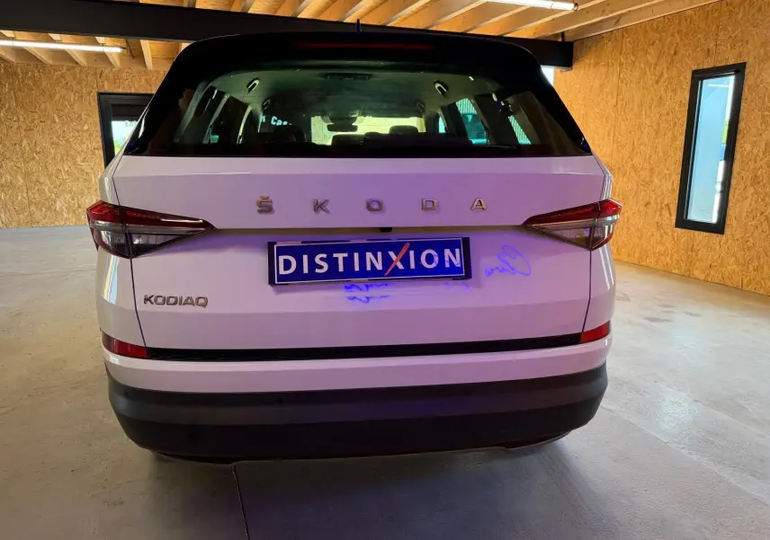 Vue intérieure côté gauche des sièges arrière en tissu noir du Skoda Kodiaq blanc 2023, avec appuie-têtes et aérateurs centraux.