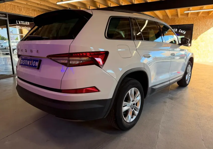 Coffre ouvert d'un Skoda Kodiaq blanc 2023, vue arrière montrant les sièges arrière relevés et l'espace de chargement.