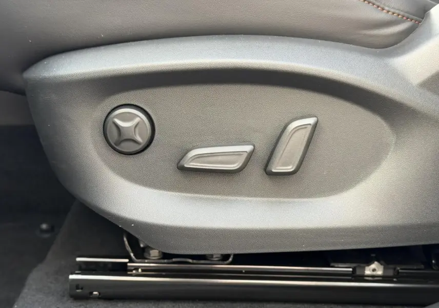 Gros plan sur les commandes de réglage électrique du siège conducteur noir du MG MOTOR EHS 1.5 Hybrid+ 224 Luxury.