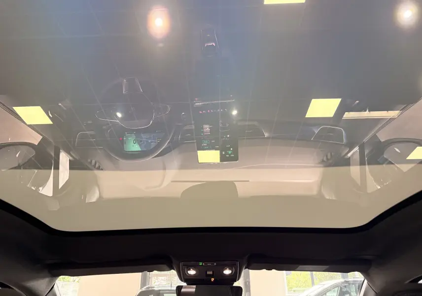 Vue intérieure du toit panoramique du Renault Symbioz gris Rafale, avec reflet du tableau de bord et écran central tactile.